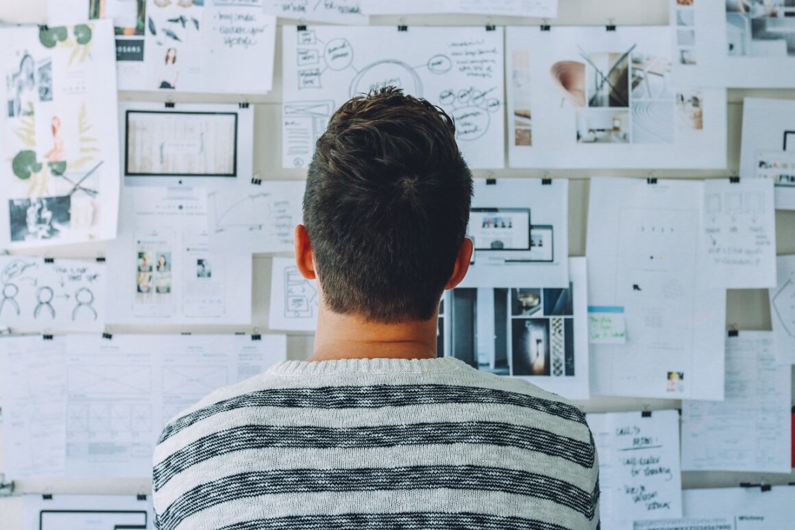 man looking at a board of different paper with options and plans